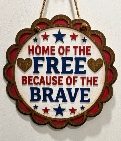 Decorative sign with 'Home of the Free Because of the Brave' text on a white background