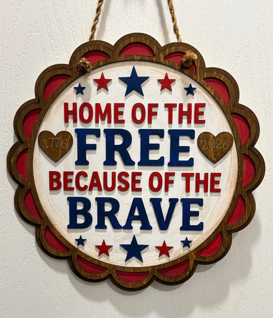 Decorative sign with 'Home of the Free Because of the Brave' text on a white background